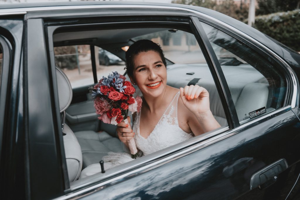 A bride in a wedding dress sitting on the back seat of a luxury car, representing the elegance and sophistication of wedding car hire Melbourne.