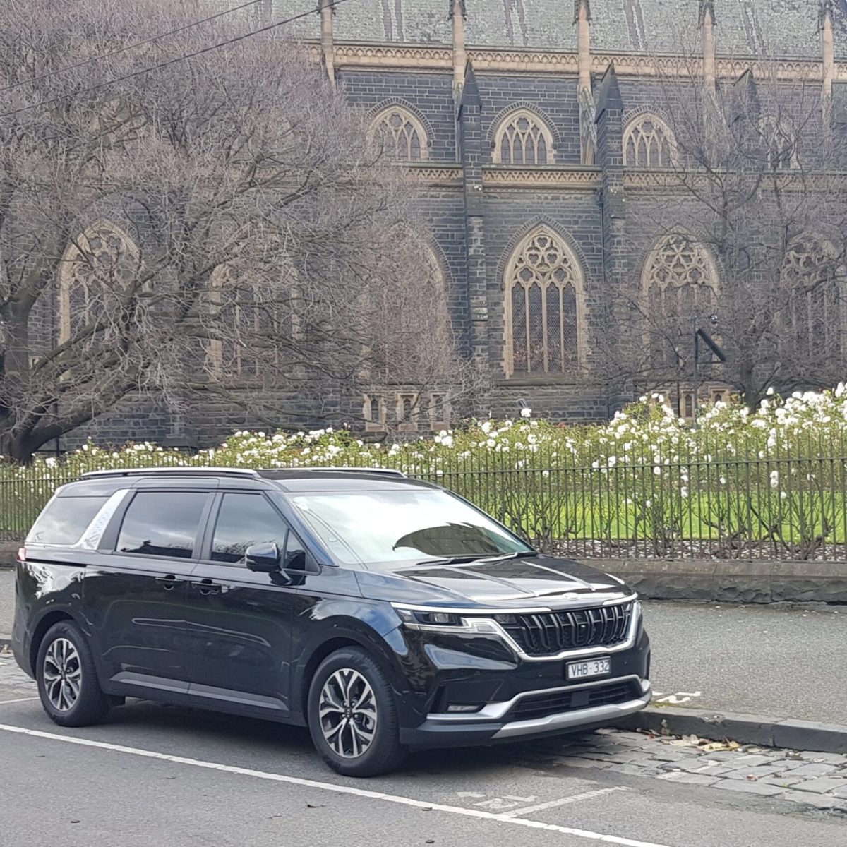 Black Kia Carnival in front of a cathedral - VHA cars Melbourne